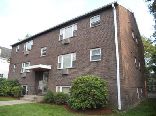 a brick apartment building with a yard in front of it